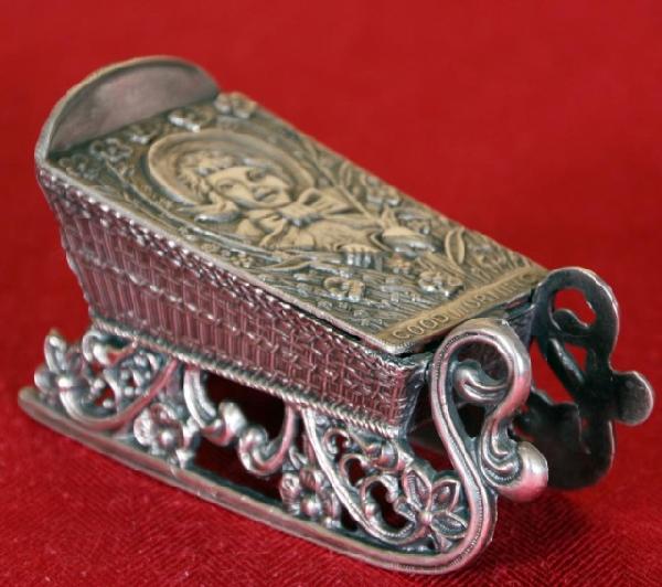 Silver Plate "Sleigh" Jewelry Casket: Silver Plate "Sleigh" Jewelry Casket. A fancy sleigh w/ a pierced filigree base and a wicker weave pattern on the side. The hinged lid shows the bust of a girl peering through a pile of brush and read