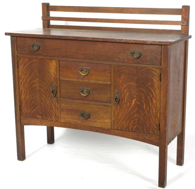Gustav Stickley No. 816 Sideboard: Gustav Stickley No. 816 Oak Sideboard. A full length drawer centered over a column of 3 drawers and doors on either side, arched lower apron, long legs, overhanging top, plate rail and hammered copper