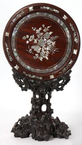 Mother Of Pearl Inlaid Table Mirror: Oriental Mother Of Pearl Inlaid Table Mirror. Carved teak wood stand, holds a round beveled mirror with mother of pearl inlay around the border and floral M.O.P. inlay on the back panel. 23 in. High x