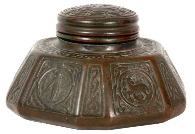 Tiffany Studios Zodiac Bronze Inkwell: Tiffany Studios Zodiac Bronze Inkwell. Large inkwell has a hexagon shape with a hinged domical lid, each side is decorated with a different zodiac symbol. Complete with glass insert, signed Tiffany St