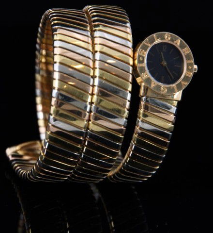 18K Bulgari Tubogas Serpent Watch: Ladies 18K Bulgari Tubogas Serpent Watch. Has a marked 18K tri-colored gold serpent style Tubogas band; round gold bezel stamped with the double logo, marked 18K gold case, signed Bvlgari, black dial