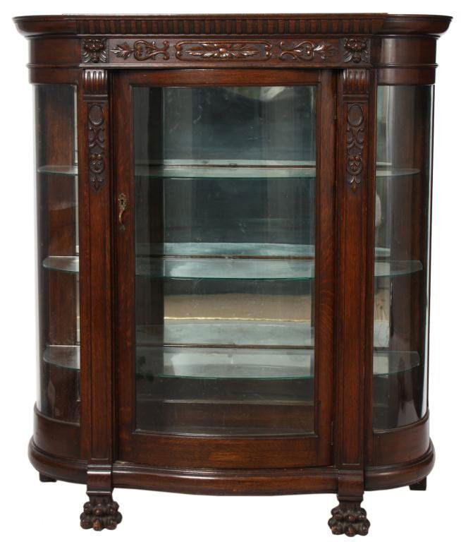 Signed RJ Horner China Cabinet: Signed R. J. Horner Carved Oak China Cabinet. Cabinet has a single door with bowed glass and bowed side glasses; carved frieze has leaf patterns and lion's heads, stands on paw feet and has a mirrored