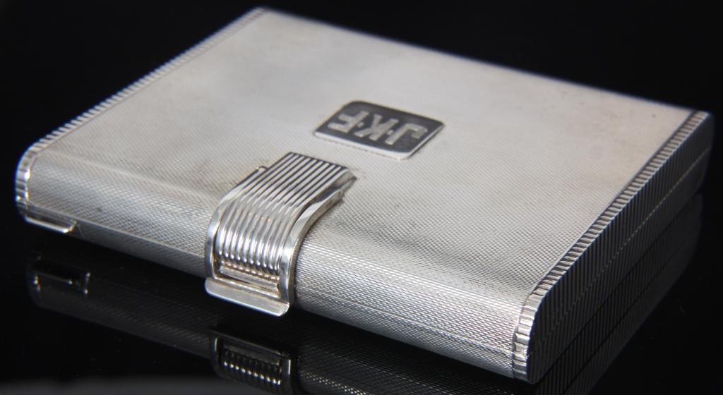 Sterling Silver Compact: Sterling Silver Compact. The large case has a knurled textured surface with rounded edges and a ribbed latch and sides, plaque on the lid is monogrammed J.K.F. The interior has a beveled mirror, 2 ope