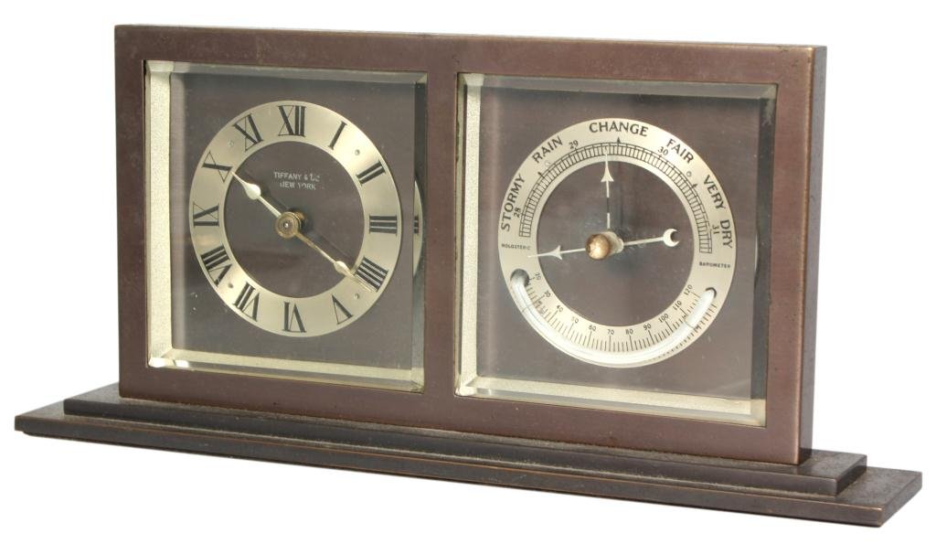 Tiffany Bronze Desk Clock: Tiffany Bronze Desk Clock. Bronze case has a timepiece on the left and barometer on the right, silvered chapter ring with black Roman hour numerals and silvered spade hands, signed Tiffany & Co. New Y