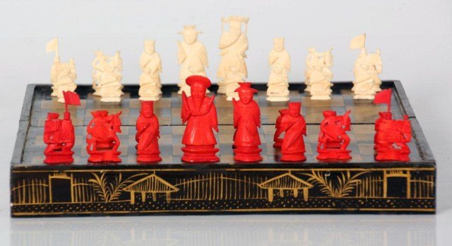 Chinese Cantonese Style Ivory Chess Set: Chinese Cantonese Style Ivory Chess Set. Ebonized wood folding game board with gilt decorations, has 32 carved ivory figural pieces with half having a red stained finish. Board is 14 in. x 14 in.