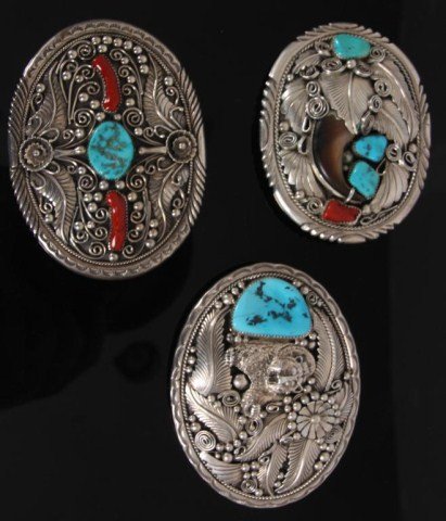 3 Sterling Silver Buckles: 3 Sterling Silver Buckles. Oval silver buckle with 3 turquoise stones, one coral and a bear claw, surrounded by leaf design, signed M. Thomas gi. Oval silver buckle with center turquoise, 2 coral ston