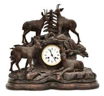 Black Forest Carved Wood Figural Mantel Clock: Black Forest Carved Wood Figural Mantel Clocklate 19th centurythe case carved with mountain goats, foliate and a tree, the porcelain dial with Roman hour numerals, eight-day brass striking movement by