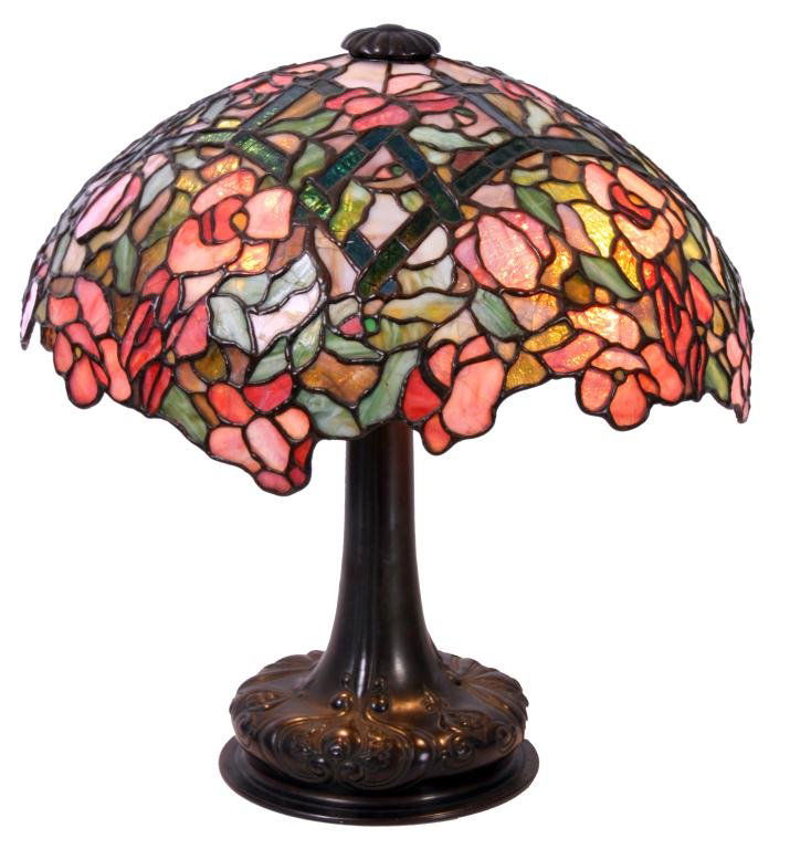 17" Gorham Leaded Floral Table Lamp: 17" Gorham Leaded Floral Table Lamp on Reed & Barton Base. The domical shade has an irregular lower rim, decorated with large pink flowers having yellow centers with green leaves, stems and amber pane