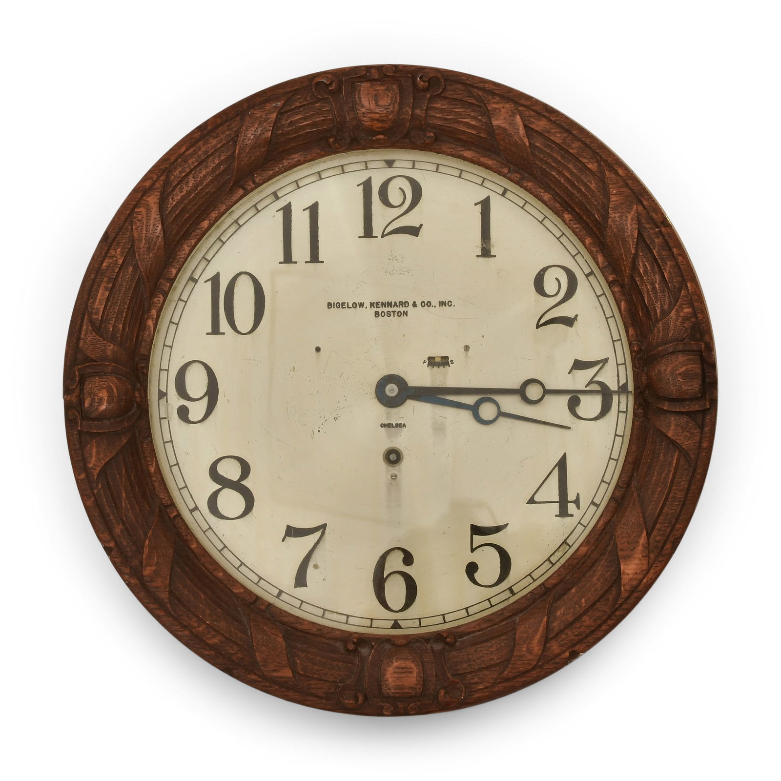 Chelsea Clock Co. Wall Clock, Retailed by Bigelow, Kennard & Co.: Chelsea Clock Co. Wall Clock, Retailed by Bigelow, Kennard & Co.circa 1910-15brass case with 10-inch silvered dial and applied wood carving to the bezel, 8-day brass time only spring driven model "F"