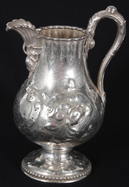 Large Coin Silver Pitcher: Large Coin Silver Pitcher. Has a bulbous body with a round and scalloped rim. Seashell, floral & leaf decorated spout and handle with fancy floral and leaf designs throughout the body and foot. The fr