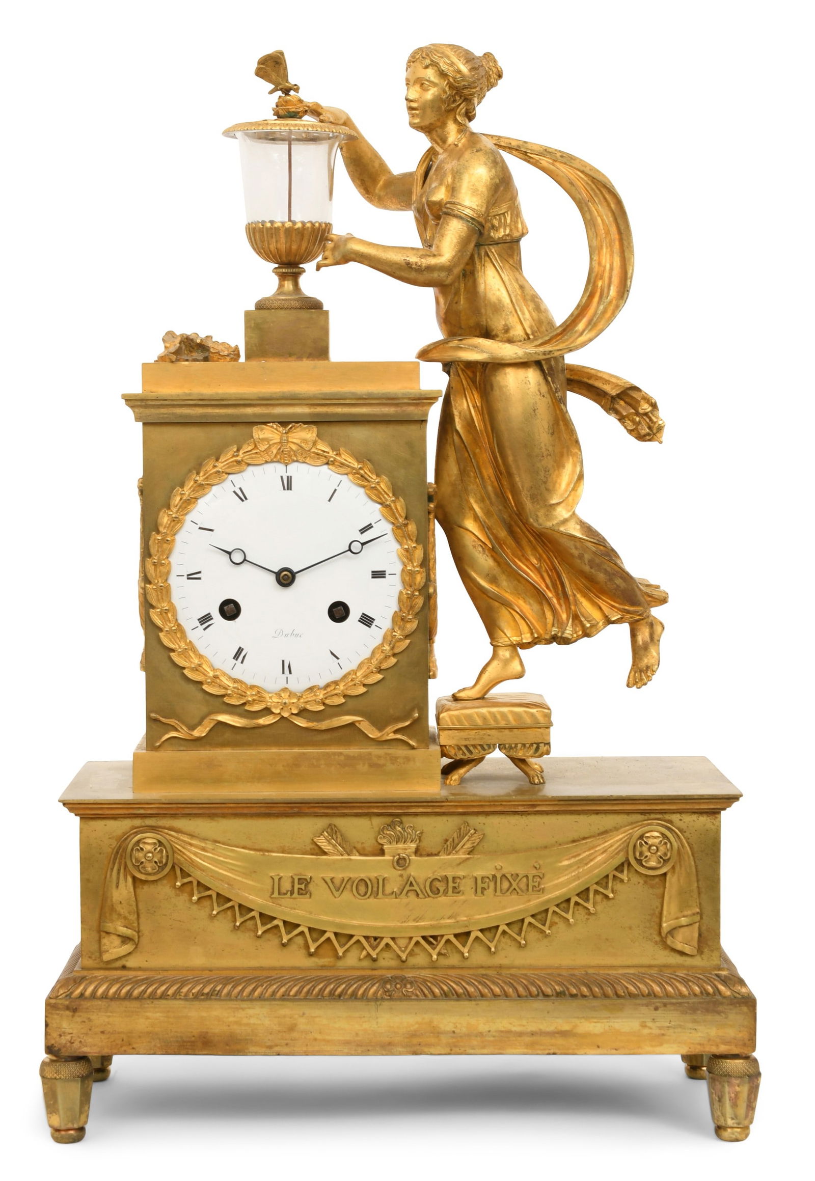 French Empire Gilt Bronze Mantel Clock by Jacques Nicolas Pierre Francois Dubuc, "Le Volage Fixe": French Empire Gilt Bronze Mantel Clock by Jacques Nicolas Pierre Francois Dubuc, "Le Volage Fixe"circa 1815surmounted by a classical robed woman reaching for a butterfly on a glass urn, 8-day brass si