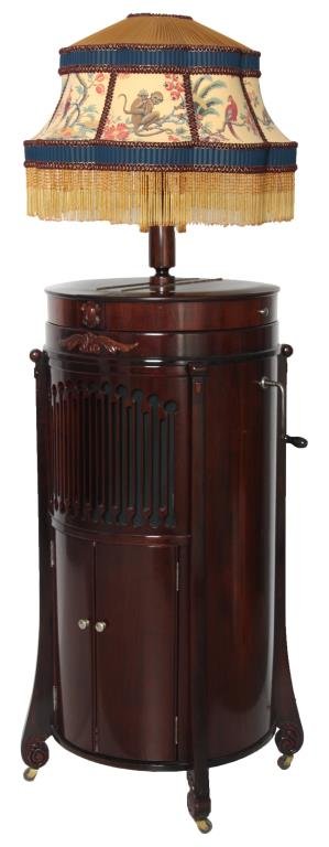 Modernola Co. Floor Lamp Model Phonograph: Modernola Co. Floor Lamp Model Phonograph. Cylindrical mahogany case with 4 long corbels having scrolling leaf carved feet; has 2 curved doors in the base with 7 tier music rack under the pierced carv