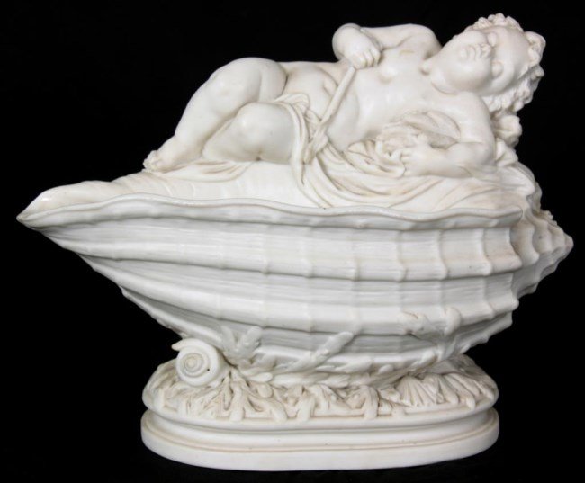 Parian Figural Putti Vase: Parian Figural Putti Vase. Recumbent figure of a putti holding a cluster of cattails in its arms, the other arm holds a long staff; the figure is lying on top of a large conch shell with the mouth of 