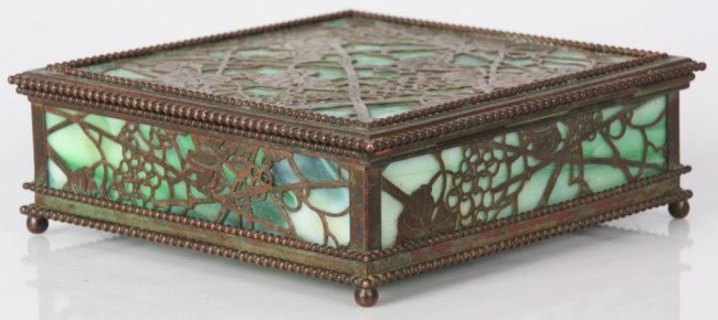 Tiffany Pine Needle Handkerchief Box: Tiffany Pine Needle Handkerchief Box. Bronze box has a pierced grape vine pattern overlaid on green glass, beaded borders around the edges, stands on ball feet and has a hinged lid; lid and front pane