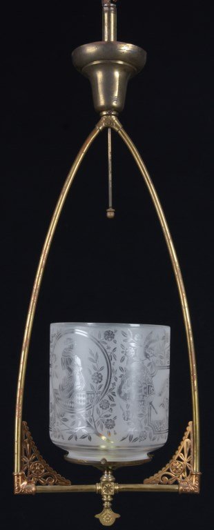 Brass Hanging Hall Light Fixture: Brass Hanging Hall Light Fixture. Has 2 brass side arms forming a harp around the shade with inverted bell shaped ceiling cap and aesthetic pierced sunflower corbels at the corners. The 7 in. cylindri