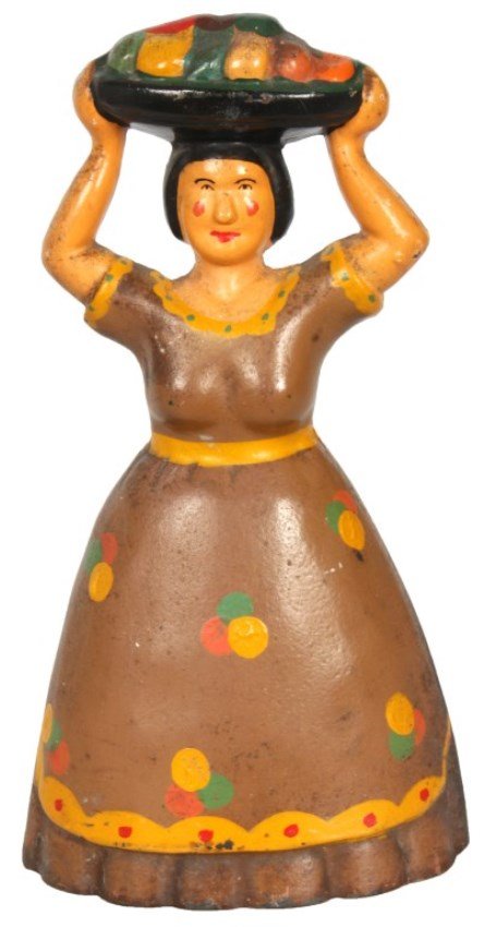Tropical Woman W/ Fruit Iron Doorstop: Tropical Woman W/ Fruit Cast Iron Doorstop. Standing figure of a woman in a brown pillow dress with polka dots, she holds a large basket of fruit up over her head. Stamped with a number 1000 on the ba