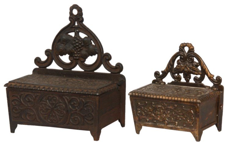 2 Victorian Cast Iron Match Holders: 2 Victorian Cast Iron Match Holders. Table top standing boxes with 4 feet, hinged lids and pierced filigree decorated back splash with filigree paneled designs. The smaller box has a lacquered brass c