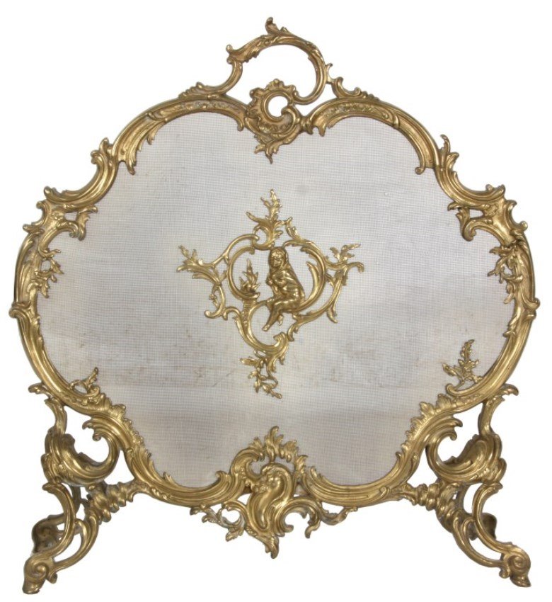 Gilt Brass Rococo Fire Screen: Gilt Brass Rococo Fire Screen. Fancy gilt brass rococo filigree style frame with crest handle and splayed feet, has a mesh screen center panel mounted with a figural putti wrapped in a blanket and sit