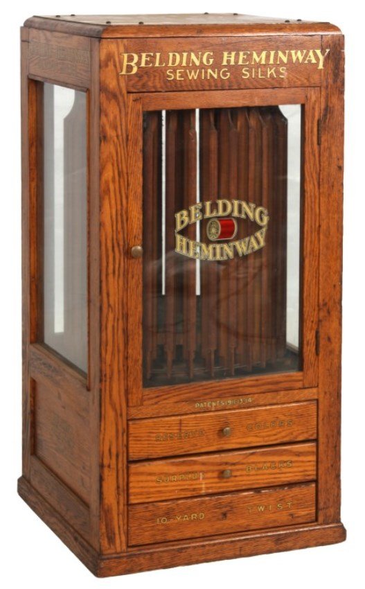 Belding Heminway Revolving Spool Cabinet: Belding Heminway Revolving Spool Cabinet. Oak case with glass panels on 4 sides over inset panels with “Belding Heminway Silks” decals around the top and on the panels; has a reverse decorated gla