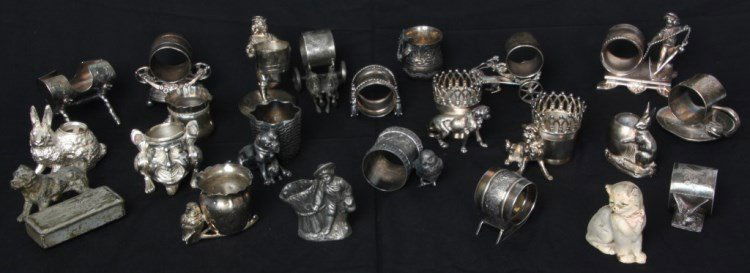 22 Pcs. Odd Silver Plate: 22 Pcs. Odd Silver Plate. Collection of silver plated napkin rings, match holders, an inkwell and a candle holder; plus a small cast iron cat.