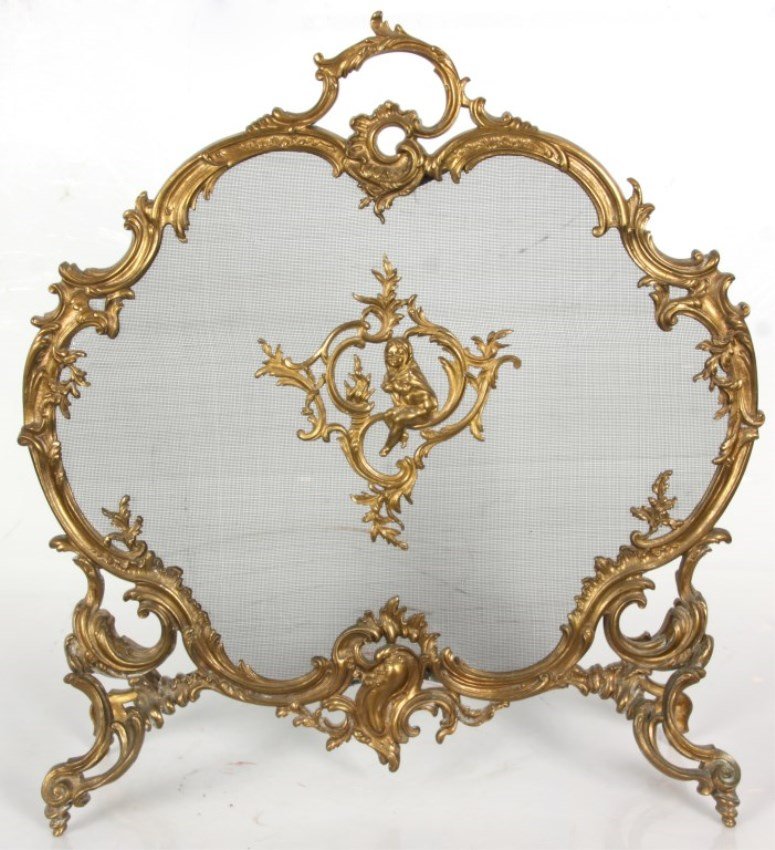 Gilt Brass Rococo Fire Screen: Gilt Brass Rococo Fire Screen. Fancy gilt brass rococo filigree style frame with crest handle and splayed feet, has a mesh screen center panel mounted with a figural putti wrapped in a blanket and sit