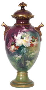 13 in. Royal Bonn Covered Urn: 13 in. Royal Bonn Covered Urn. Green and purple background with gilt highlights, gilt handles and domical lid with floral finial, decorated with colorful flowers on the front and back. Signed on the