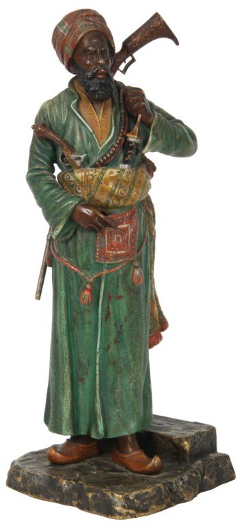 Attr: Franz Bergman Cold Painted Bronze Sculpture: Attr: Franz Bergman Cold Painted Bronze Sculpture. Standing figural of an Arab man wearing long green garments, a sash tied at his waist with dagger & pistol tucked in, rifle and bag are slung across 