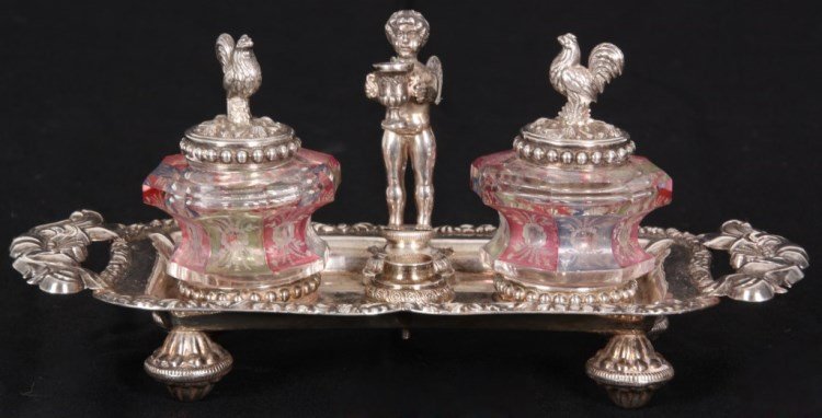Austrian-Hungarian Silver Inkwell: Austrian-Hungarian Silver Inkwell. Silver repousse tray standing on fancy feet with open handles on the sides, has a standing figural winged putting in the center holding a cup with a pen holder in th