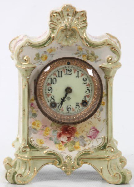 Ansonia & Royal Bonn China Clock: Ansonia & Royal Bonn China Clock. Signed Royal Bonn porcelain case with seashell crest, pale green and white background is paint decorated with beautiful flowers and gilt highlights, stands on 4 scrol