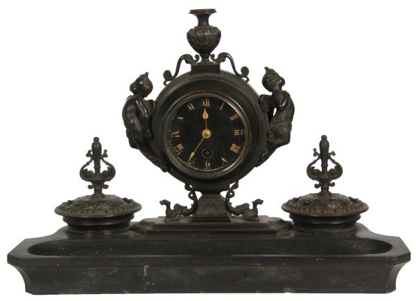 Marble & Bronze Desk Clock: Marble & Bronze Desk Clock. Black marble base with carved pen holder in the front, figural bronze inkwells with hinged lids, glass inserts and pierced finials on either side of the bronze clock tower 