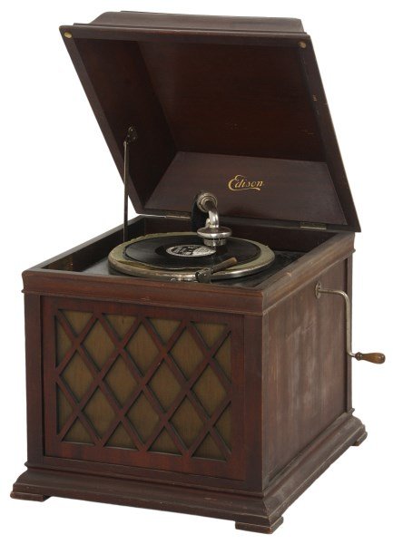 Edison Model B19 Table Top Phonograph: Edison Model B19 Table Top Phonograph. Mahogany table top case also known as the Chalet, has a domed lid with Edison decal underneath and a pierced carved speaker fender with fabric backing; spring dr