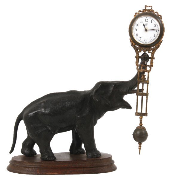 Junghans Figural Elephant Swinger Clock: Junghans Figural Elephant Swinger Clock. Standing spelter figure of an elephant facing right with its trunk turned up and facing forward; 9.5 in. long pierced decorated brass gridiron pendulum with a 