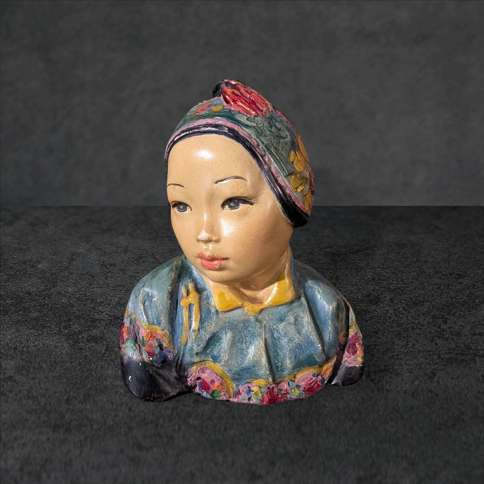 Esther Hunt â€œJonquilâ€ Painted Chalkware Bust, c.1917: Painted chalkware bust titled â€œJonquilâ€ by Esther Hunt, created circa 1917. Featuring a vibrant depiction of a child in traditional attire adorned with colorful floral patterns. Signed by 