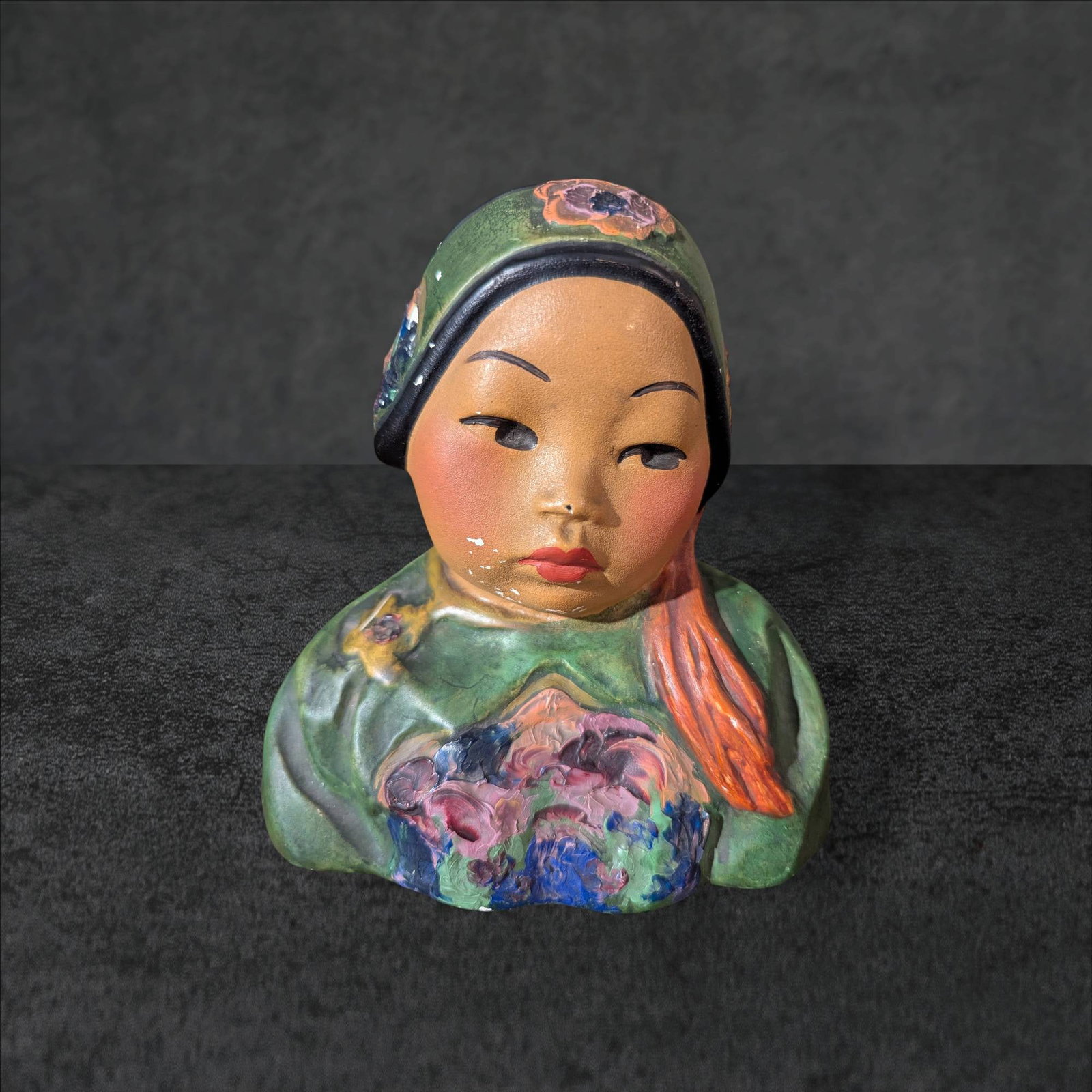 San Toy Esther Hunt Chalkware Bust, Circa 1927, 7 x 7 x 4 Inches: Chalkware bust by artist Esther Hunt titled 'San Toy,' circa 1927. Depicts a stylized child with delicately painted facial features, dressed in vibrant green attire with accents of floral detailing on