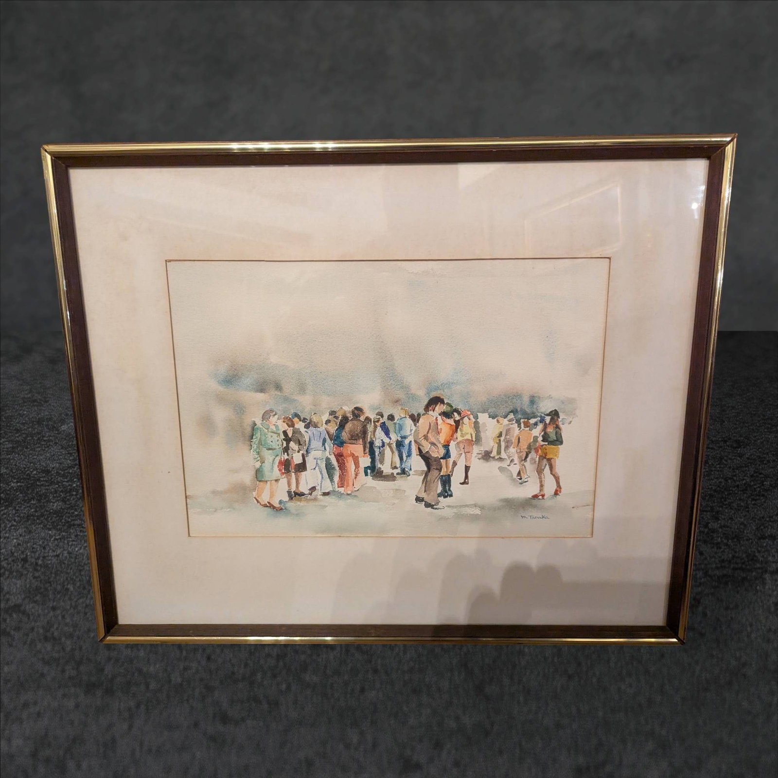 Original Watercolor Painting Depicting a Crowd, Signed M. Tanika: Original watercolor painting signed 'M. Tanika' in the lower right corner. The scene depicts a group of people in an abstract outdoor setting. The image is framed under glass with an overall dimension