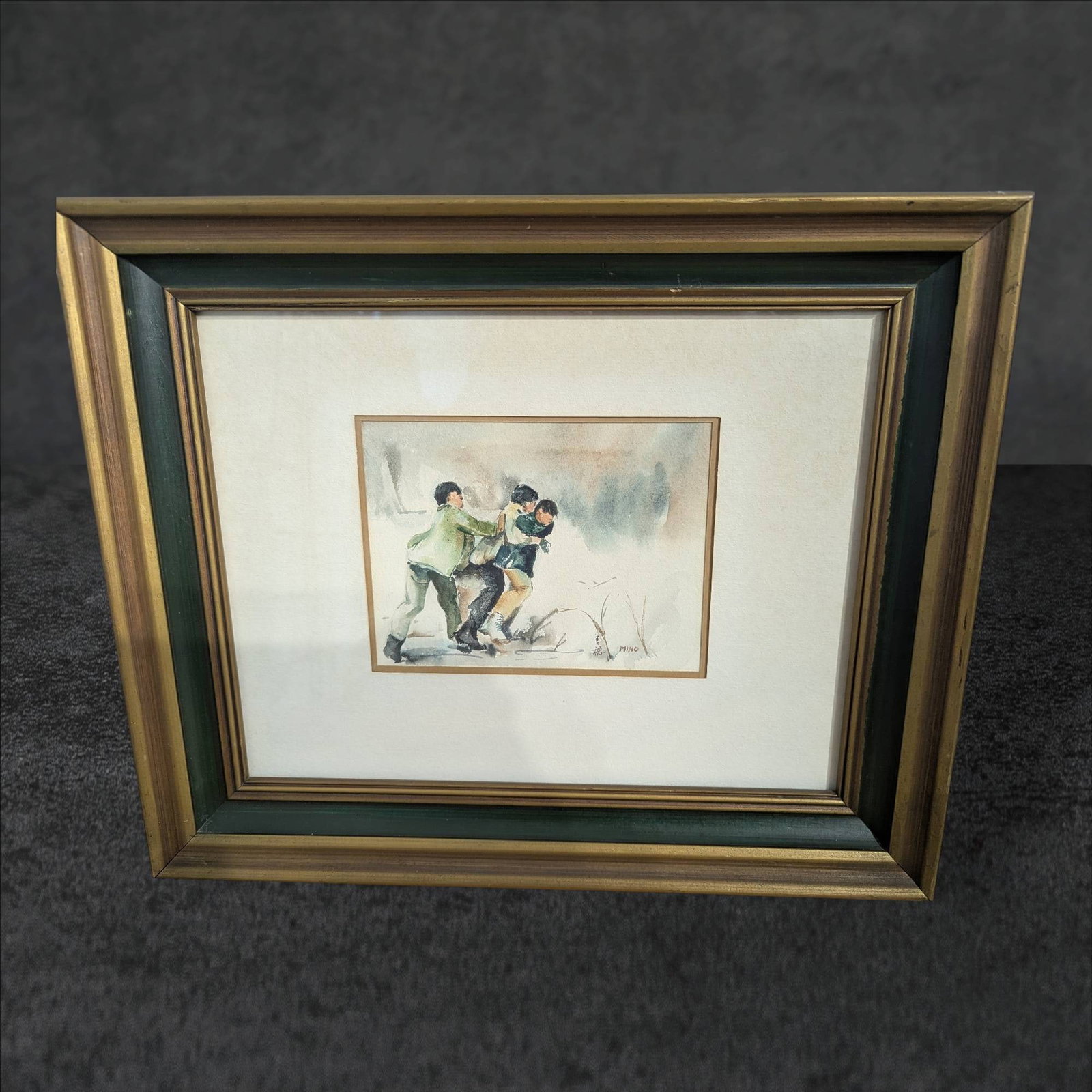 Framed Watercolor Painting Signed â€˜Mihoâ€™ Depicting Three Figures in Motion: Original watercolor painting signed 'Miho,' housed in a double-matted and wooden frame. The outer frame measures 17 1/2 in x 14 1/4 in. The artwork depicts three figures in motion against a muted back