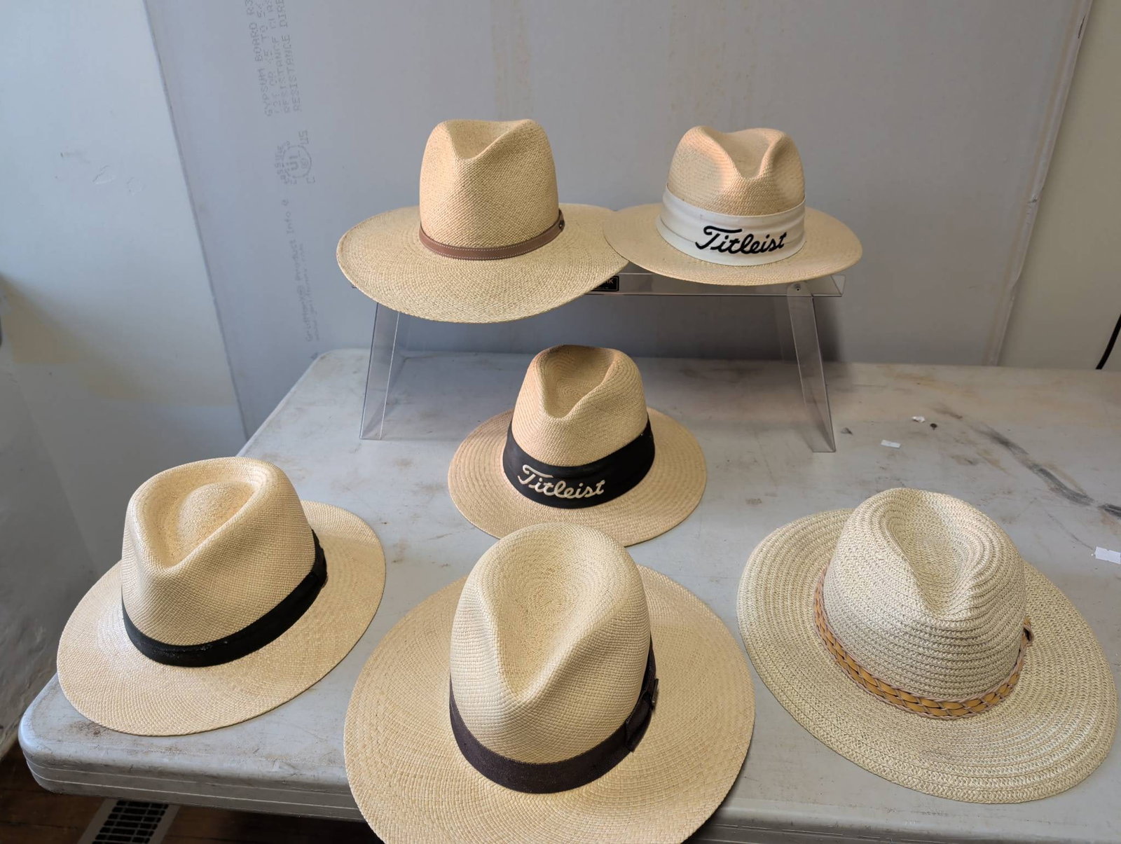 Six Straw Hats Featuring Titleist and Orvis Labels: Collection includes six straw hats, with three bearing Titleist logos and one labeled as Orvis on its interior. The hats feature various band designs, including brown leather and fabric bands. Items s