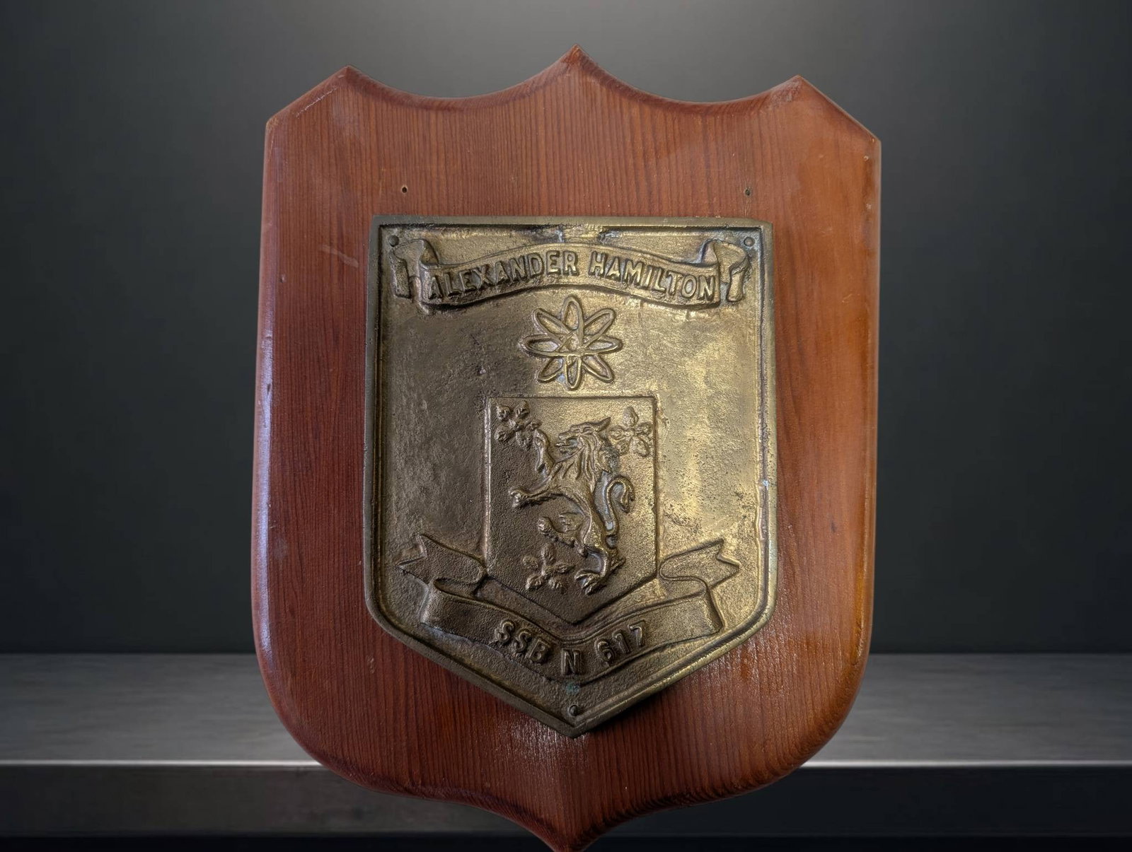 Bronze Naval Plaque for Submarine Alexander Hamilton SSBN: Bronze placard mounted on a wood shield-shaped backing, commemorating the submarine Alexander Hamilton (SSBN). The placard features embossed designs, including text and crests. It measures approximate