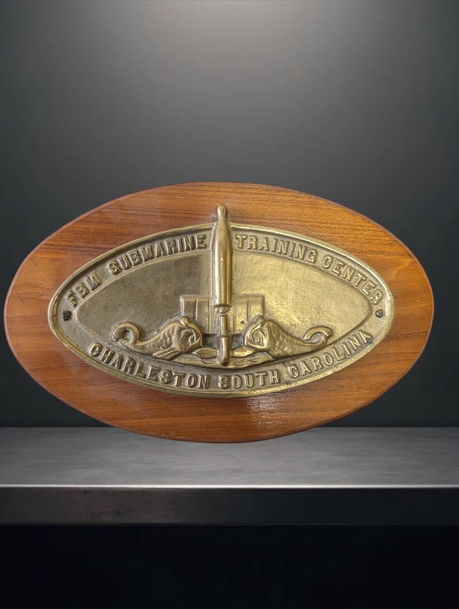 FBM Submarine Training Center Charleston, South Carolina Placard with Brass Crest: An oval wooden placard featuring a brass crest reading 'FBM Submarine Training Center Charleston, South Carolina.' The brass crest is secured to the wood, and the placard measures approximately 11 inc