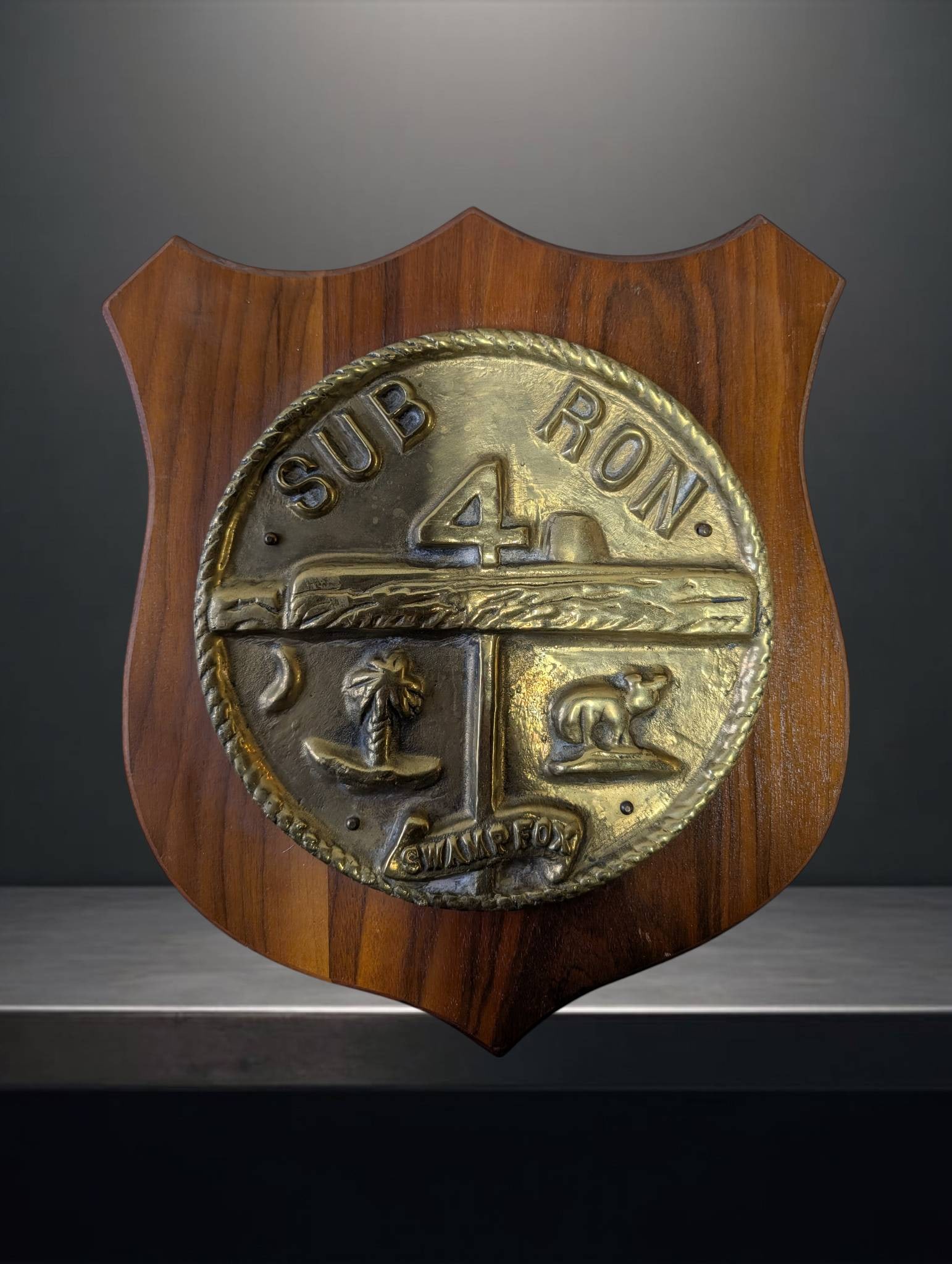 Submarine Squadron 4 Crest Plaque Featuring â€˜Swamp Foxâ€™ Design: Wooden shield-shaped plaque measuring approximately 10 x 12 inches, displaying the metal crest for Submarine Squadron 4 ('Sub Ron 4'). The crest features intricate details, including the 'Swamp Fox' m