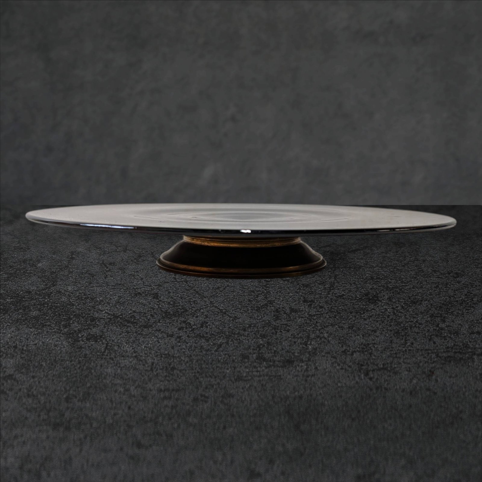 Large Amethyst Glass Cake Plate with Brass Base: Amethyst glass cake plate measuring 13 inches in diameter and 1 3/4 inches in height. Features a smooth surface and a slightly raised central design. The piece is supported by a circular brass base wi