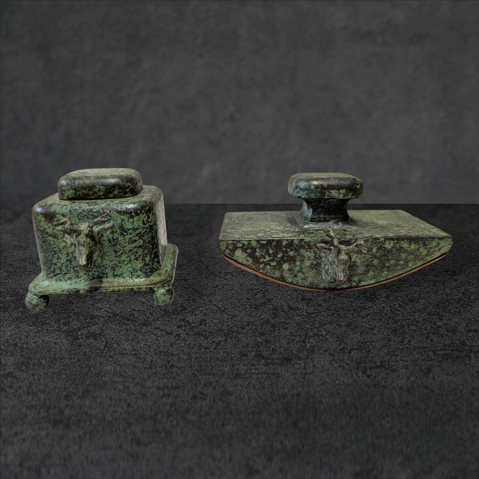 Patinated Metal Inkwell and Rocker Blotter with Stag Ornament: A patinated metal inkwell and rocker blotter set featuring a stag motif. The inkwell measures approximately 2.5 in x 2.5 in and includes a hinged lid and decorative embellishments. The rocker blotter 