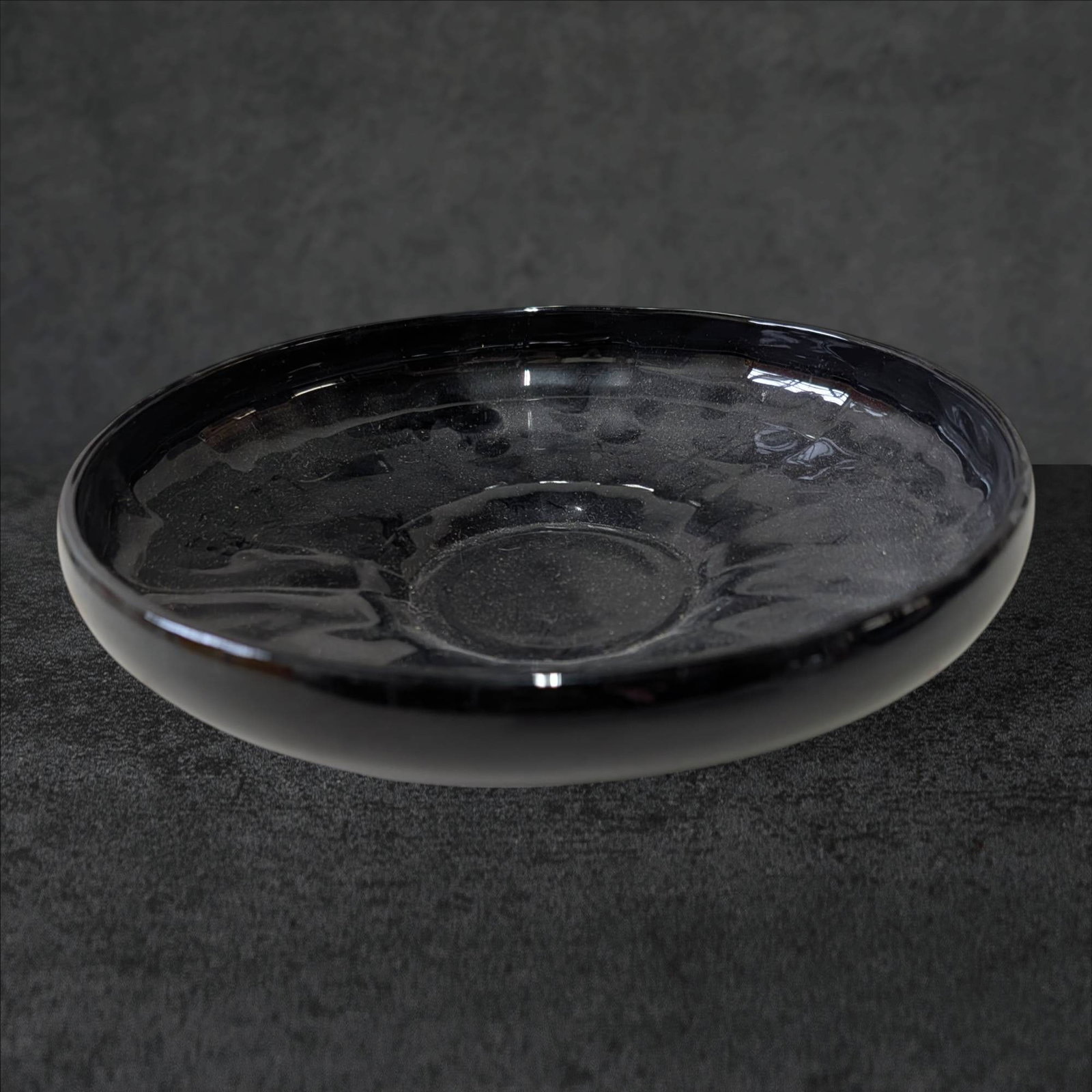 Black Amethyst Glass Pedestal Bowl, 8.5 Inches in Diameter: Black amethyst glass pedestal bowl measuring approximately 8.5 inches in diameter. Features a smooth rim, slightly flared sides, and a detailed starburst pattern on the base. The glass exhibits its ch