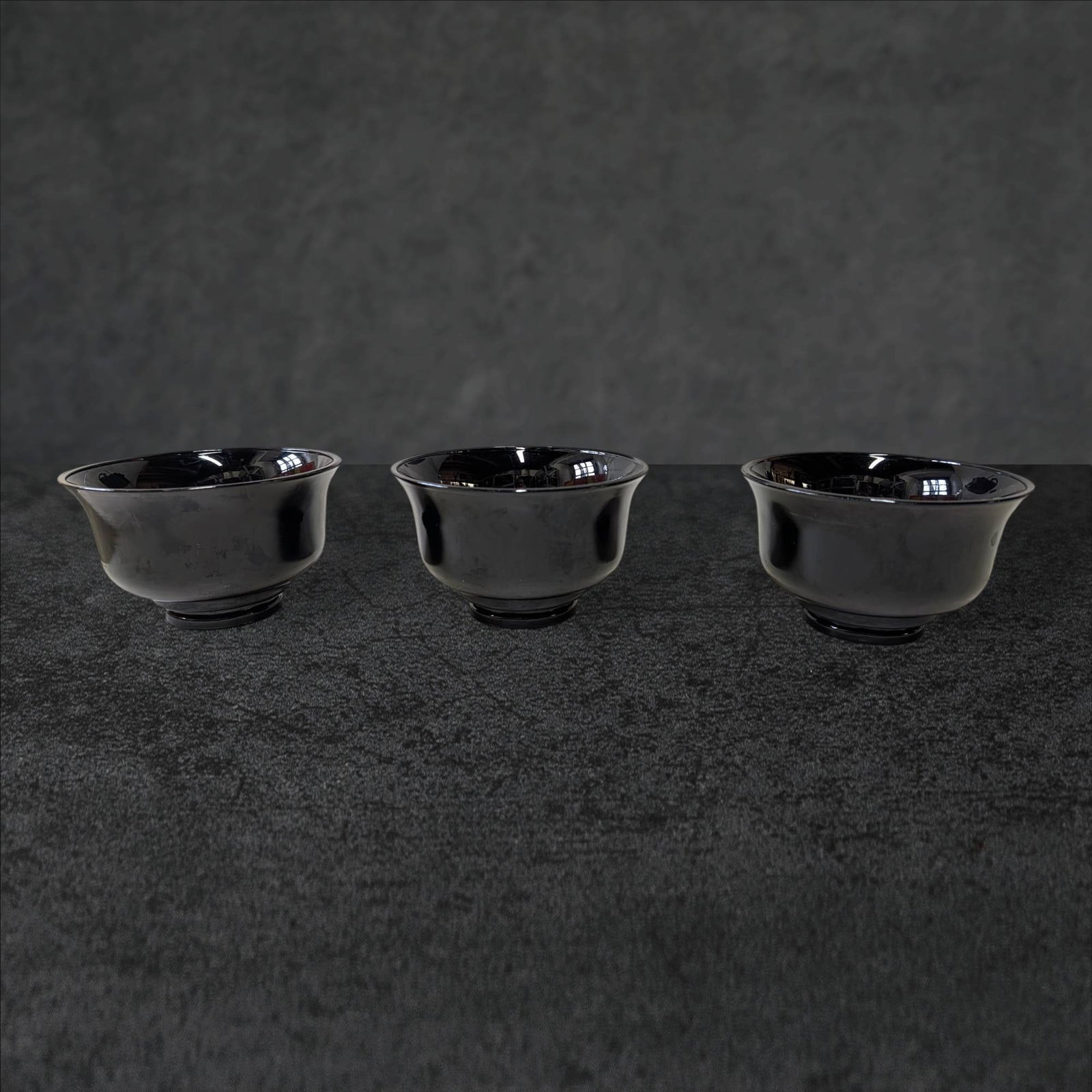 Three Amethyst Glass Bowls with Pedestal Bottoms: Three amethyst glass bowls featuring pedestal bottoms. Each bowl has a diameter of approximately 5 1/4 inches and stands about 3 1/4 inches tall. The dark amethyst glass displays a deep, rich coloring
