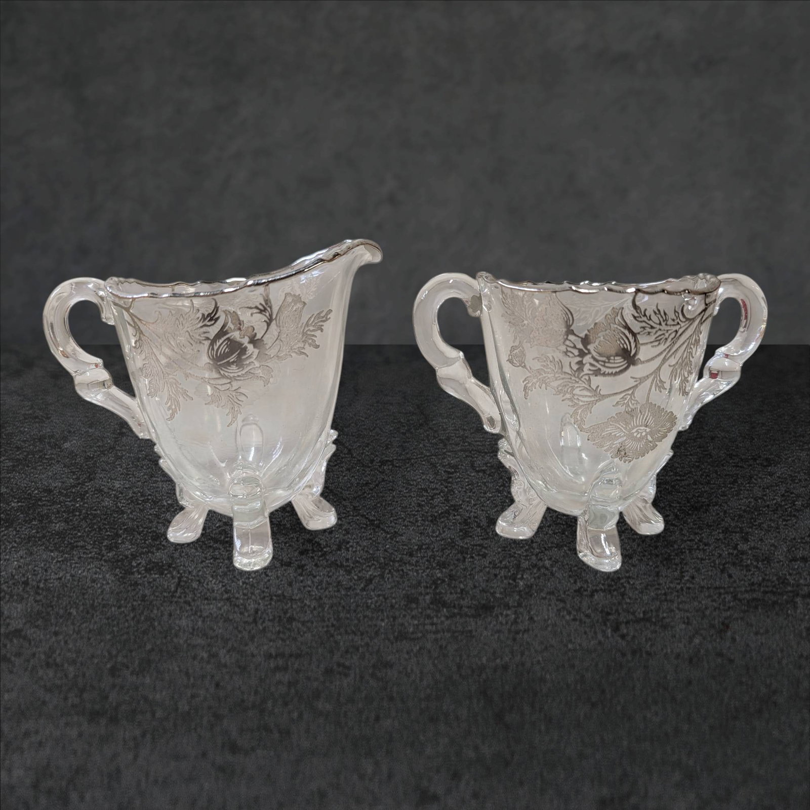 VTG Flanders Silver City Poppy Footed Glass Creamer and Sugar Set with Silver Overlay: A vintage Flanders Silver City footed glass creamer and sugar bowl set featuring intricate silver overlay with a poppy motif. The set includes a creamer with a pour spout and a double-handled sugar bo