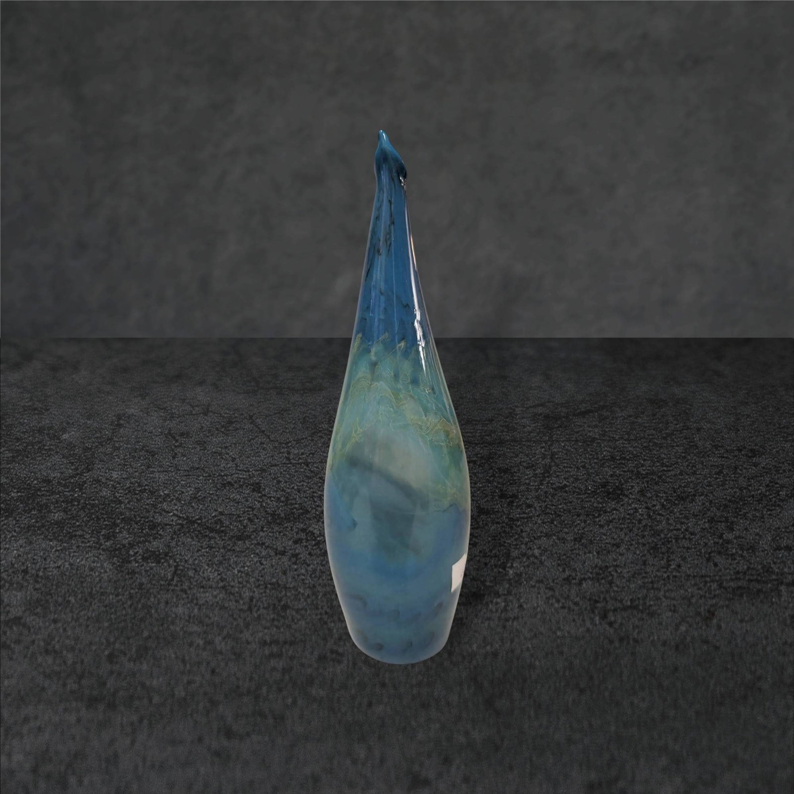 Hand-Blown Art Glass Vase, 7 3/4 in Tall, Blue and Green Tones: Hand-blown art glass vase measuring approximately 7 3/4 inches tall. The vase features an elongated form with a tapered neck and a pointed top. It displays swirling blue and green tones with a smooth,