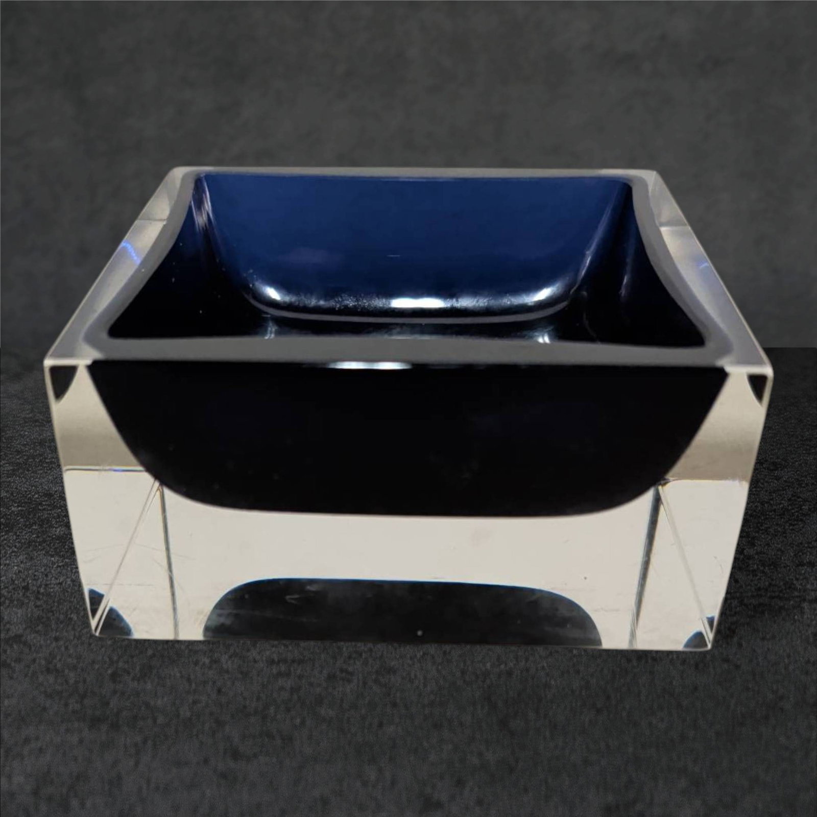 Signed Art Glass Trinket Jar in Cobalt Blue with Clear Glass Base: Square-shaped art glass trinket jar featuring a cobalt blue bowl encased in clear glass. Signed along the edge, though the signature is partially visible in the images. Dimensions are approximately 4 