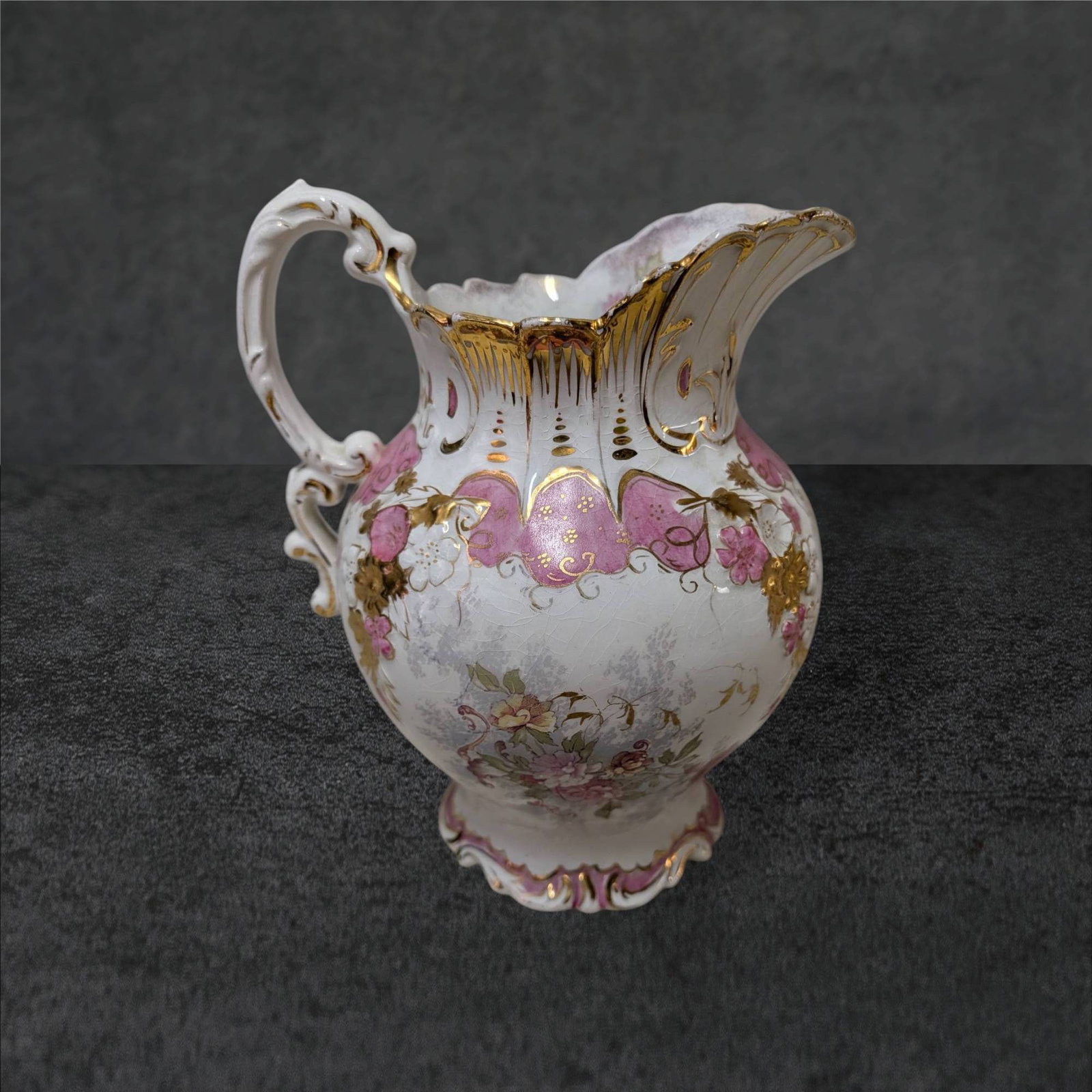 Crown Semi-Vitreous Floral Pitcher with Gold Accents, 8 in Tall: Porcelain pitcher by Crown Semi-Vitreous, standing 8 inches tall. Decorated with pink floral motifs and gold accents, featuring a scalloped rim and ornate handle. The base bears the Crown Semi-Vitreou