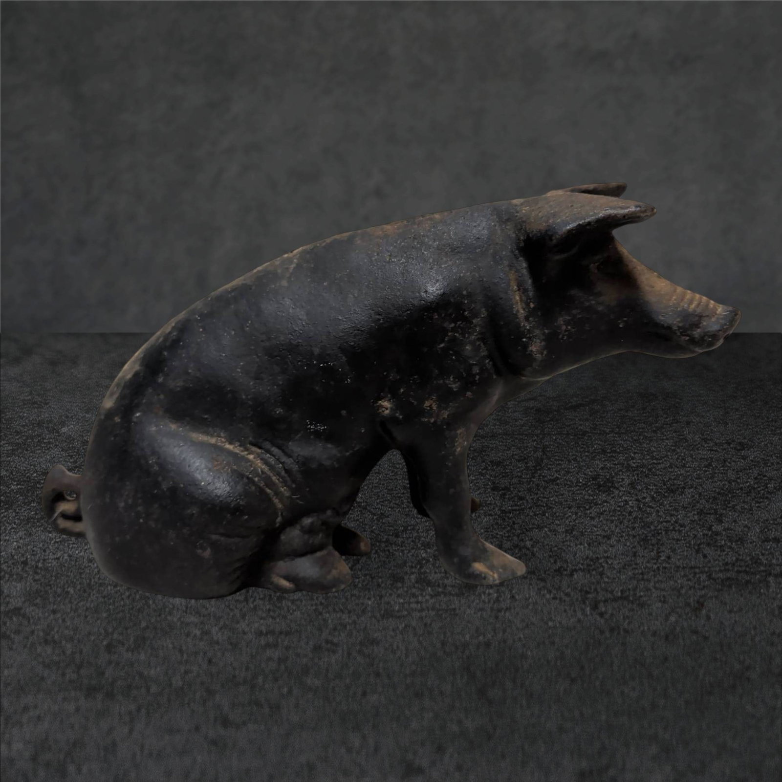 Cast Iron Pig Piggy Bank, 12 Inches Long: Cast iron pig-shaped piggy bank measuring approximately 12 inches in length. Black-painted finish with visible wear consistent with use and age. Features a slot on the top for coin insertion and a sea