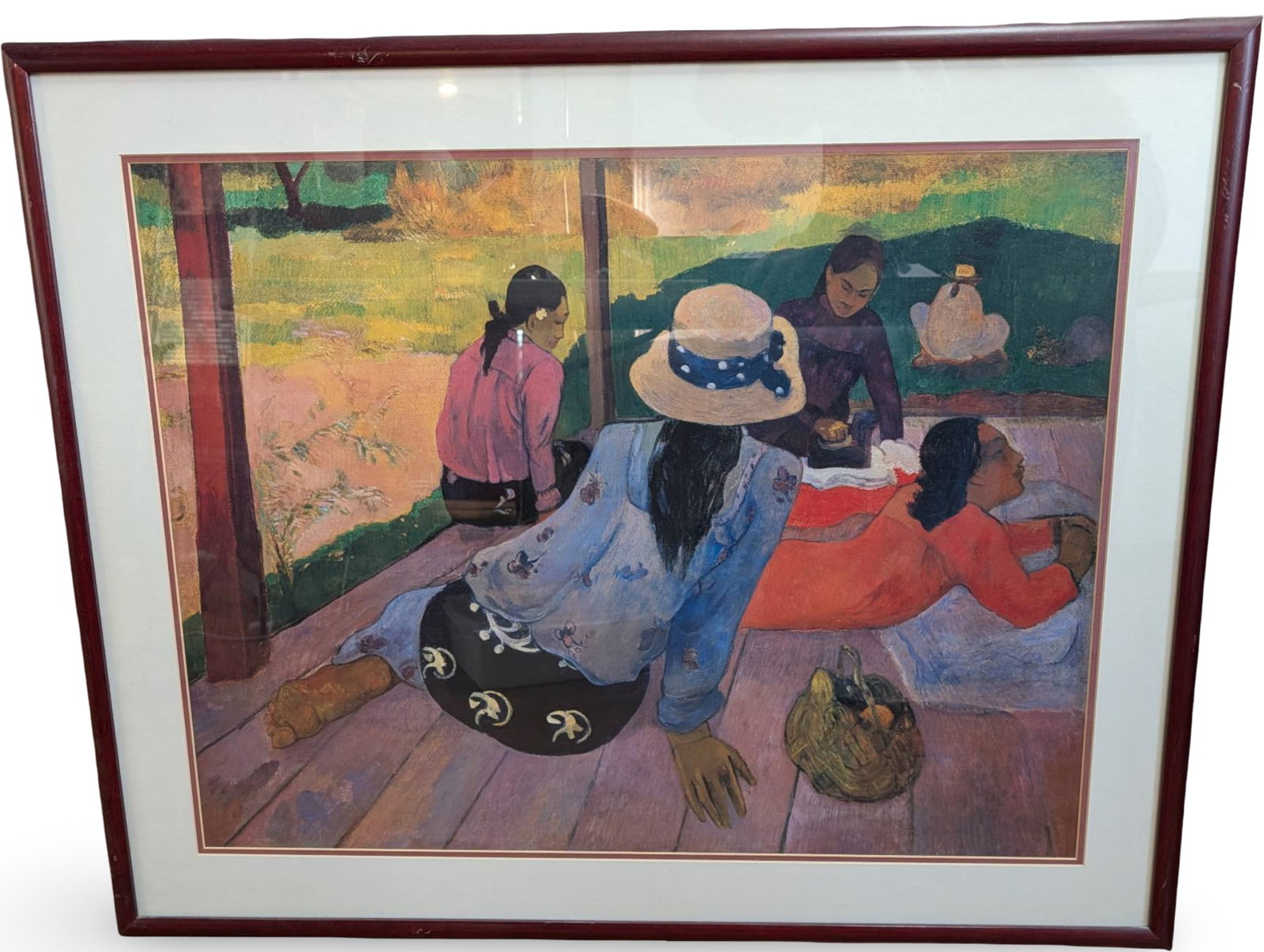 Framed Color Print of Seated Figures After Paul Gauguin: Framed color print depicting a composition of seated figures in a tranquil outdoor setting, inspired by the style of Paul Gauguin. The print measures 41 in. x 33 in., and it is housed in a burgundy-co